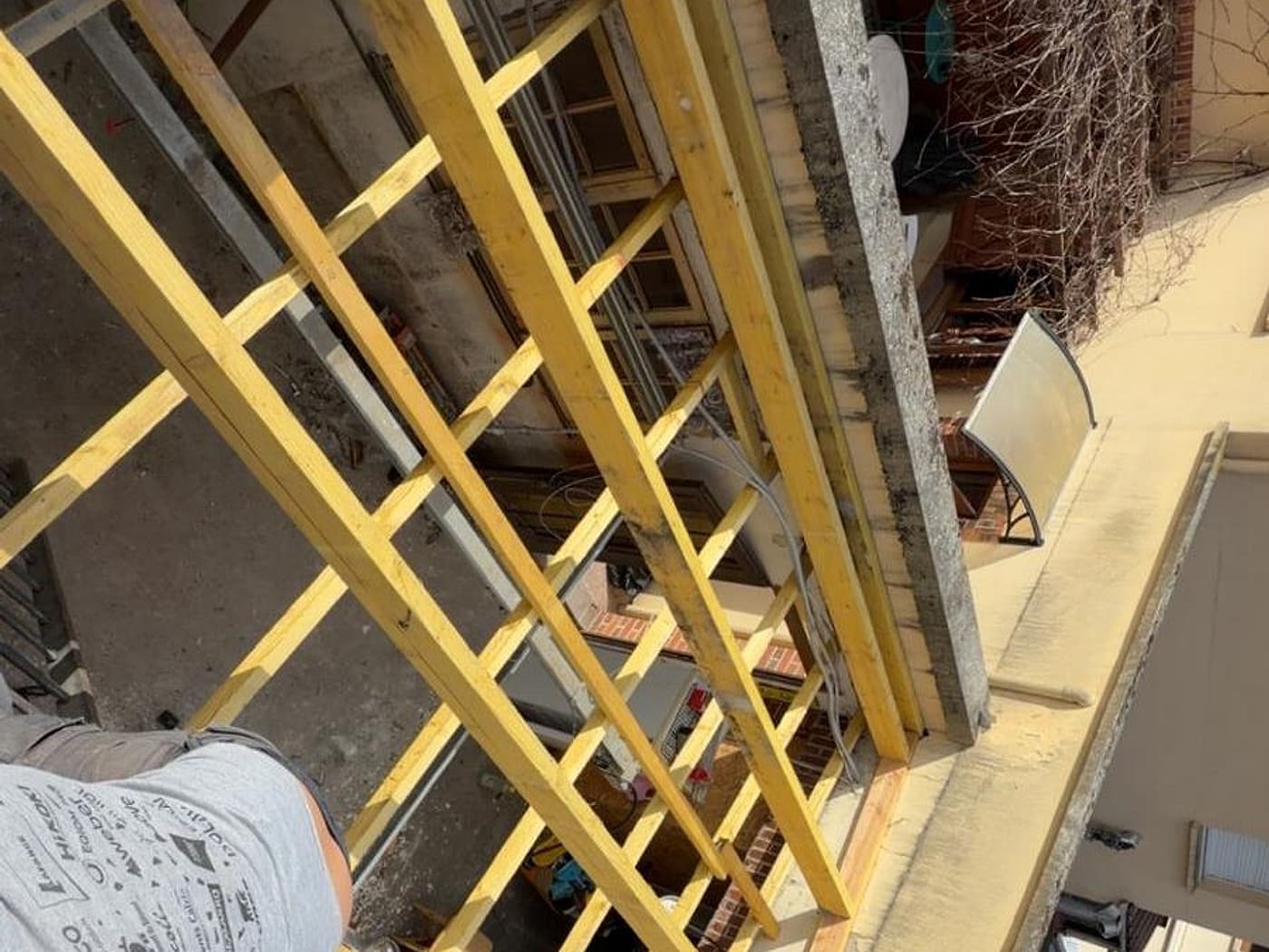 Charpente neuve en cours de pose sur une annexe, chevrons et liteaux apparents
