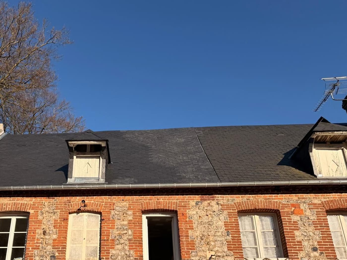 Versant terminé en ardoise avec ses lucarnes, faîtage et égout en zinc