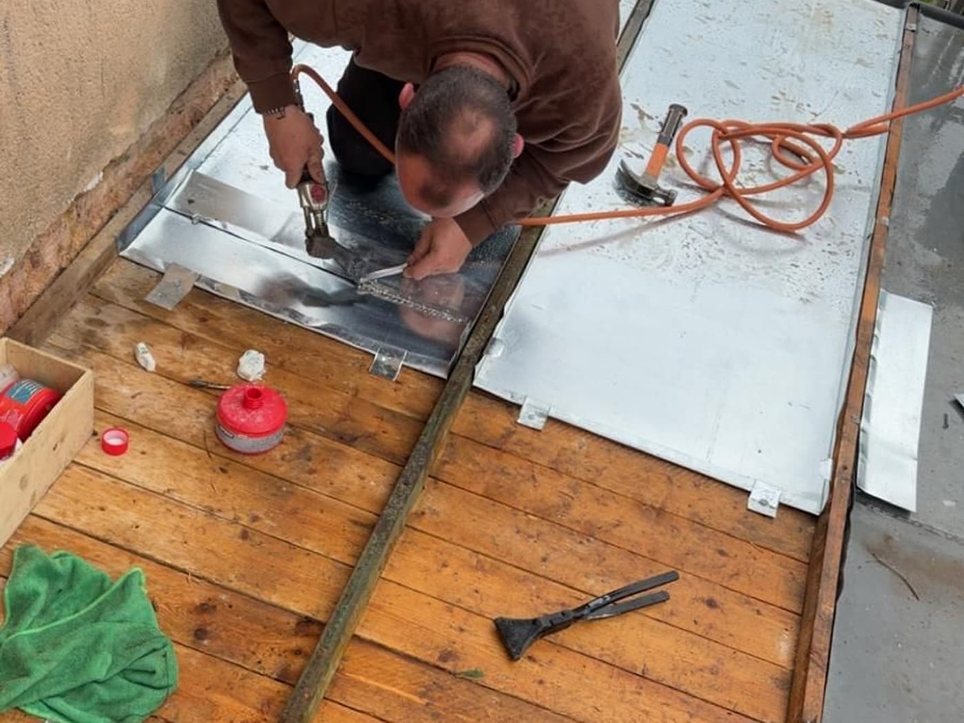 Soudure à l'étain d'un relevé en zinc au fer, sur une toiture de faible pente