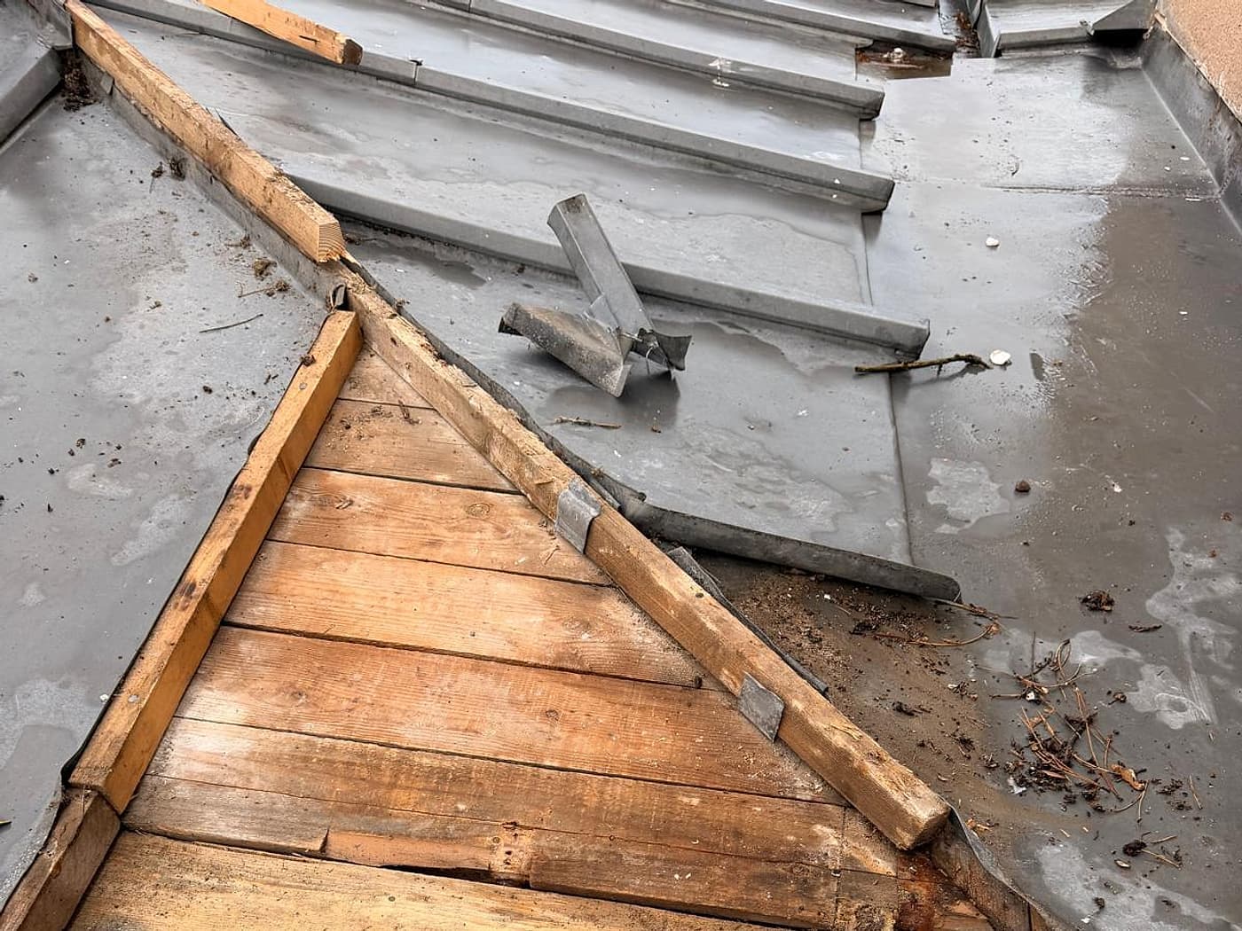 Ancien zinc déposé, voligeage mis à nu sur une toiture de faible pente